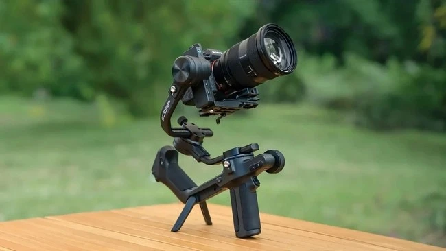 FeiyuTech Scorp 2 стоїть на столі на власних вбудованих опорних ніжках з камерою Sony та світлосильним зумом; чітко видно інтегровану Т-подібну конструкцію подвійного хвату