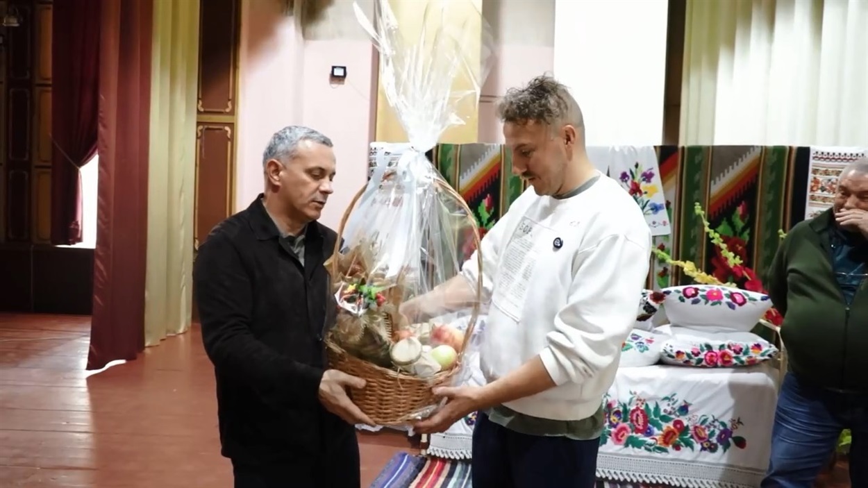 Сергій Мазур вручає Євгену Клопотенку корзину з місцевими смаколиками 